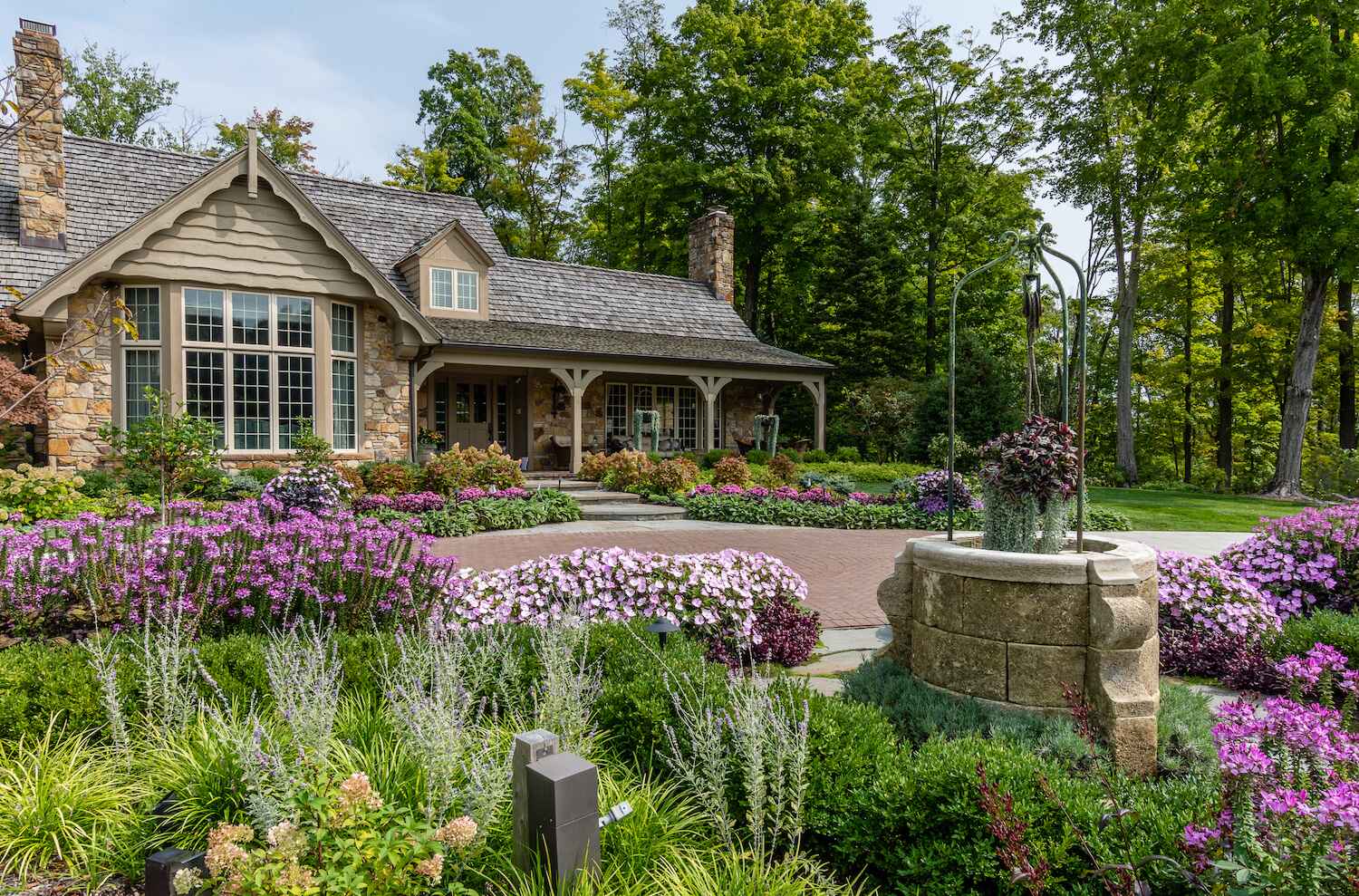 Colorful front yard landscape design with flowers, stone walkway, and rustic home in Moreland Hills, Ohio by Exscape Group