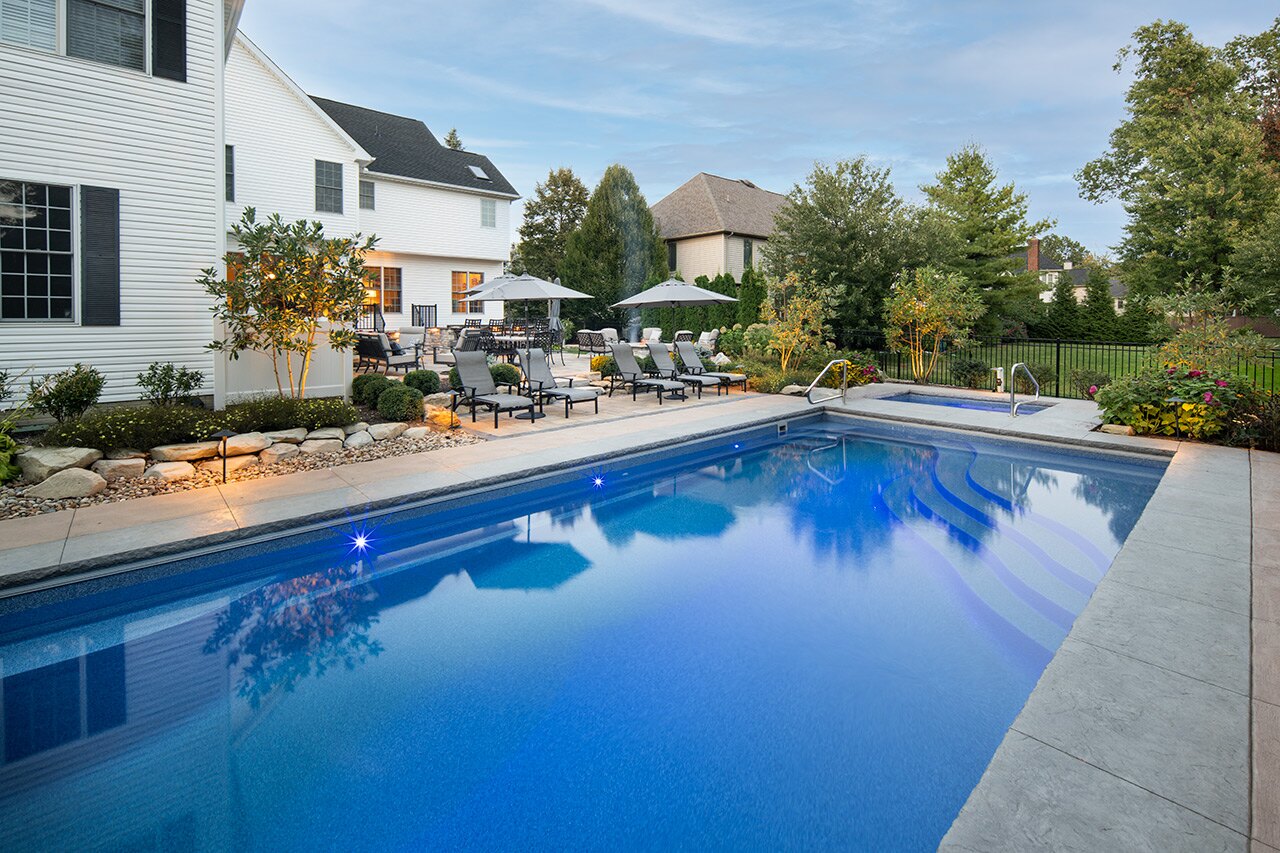 Inground pool and paver deck behind a newer two-story home