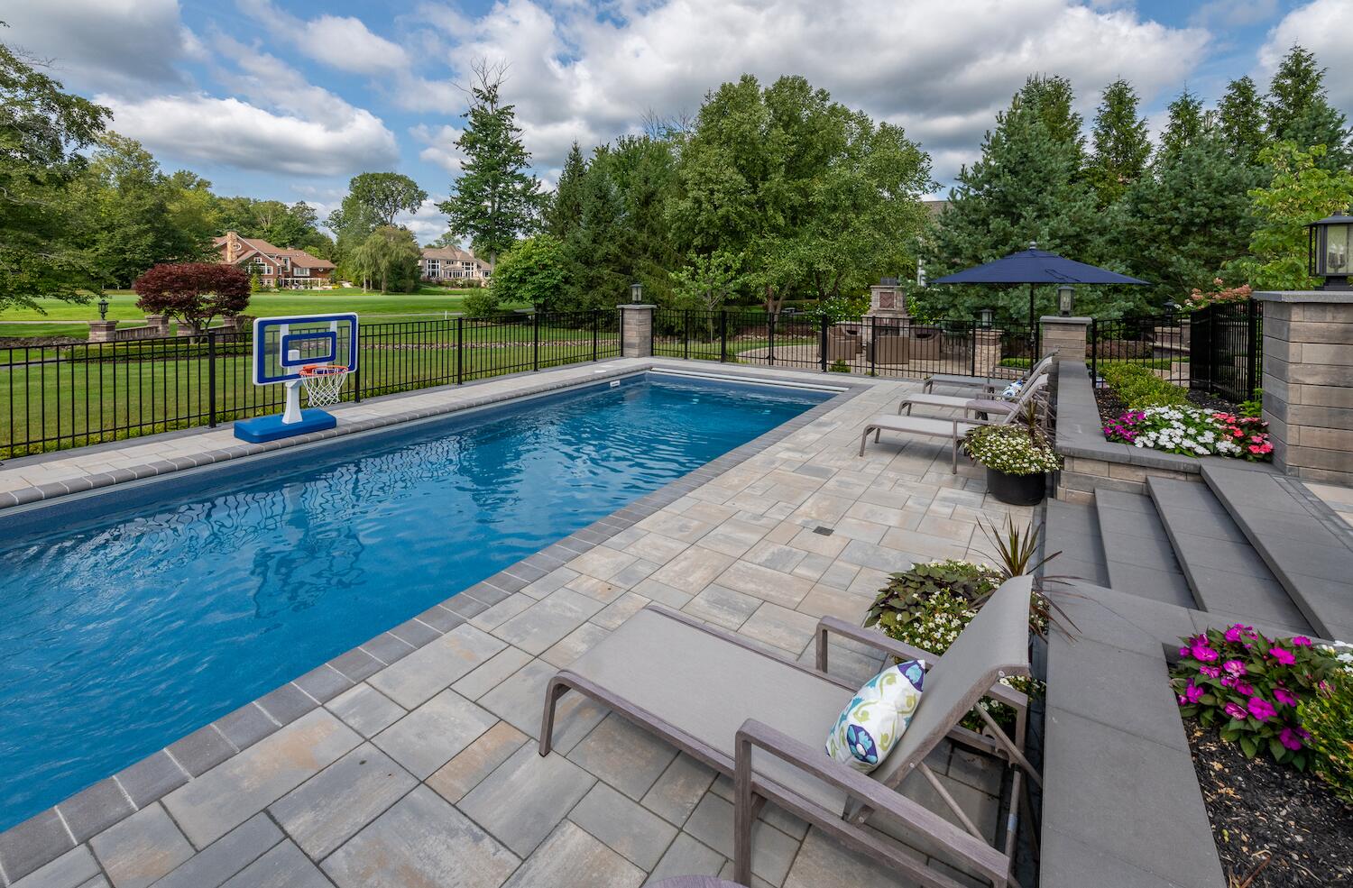 Expansive pool deck with custom pavers and stylish lounge chairs in Moreland Hills, OH