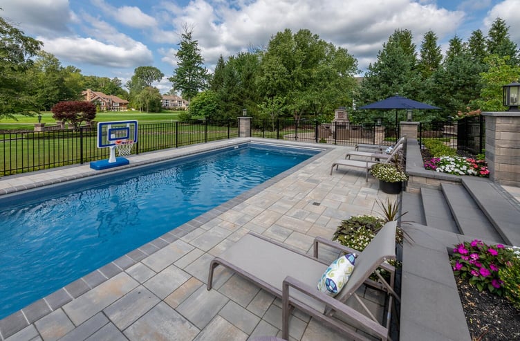 Expansive pool deck with custom pavers and stylish lounge chairs in Moreland Hills, OH