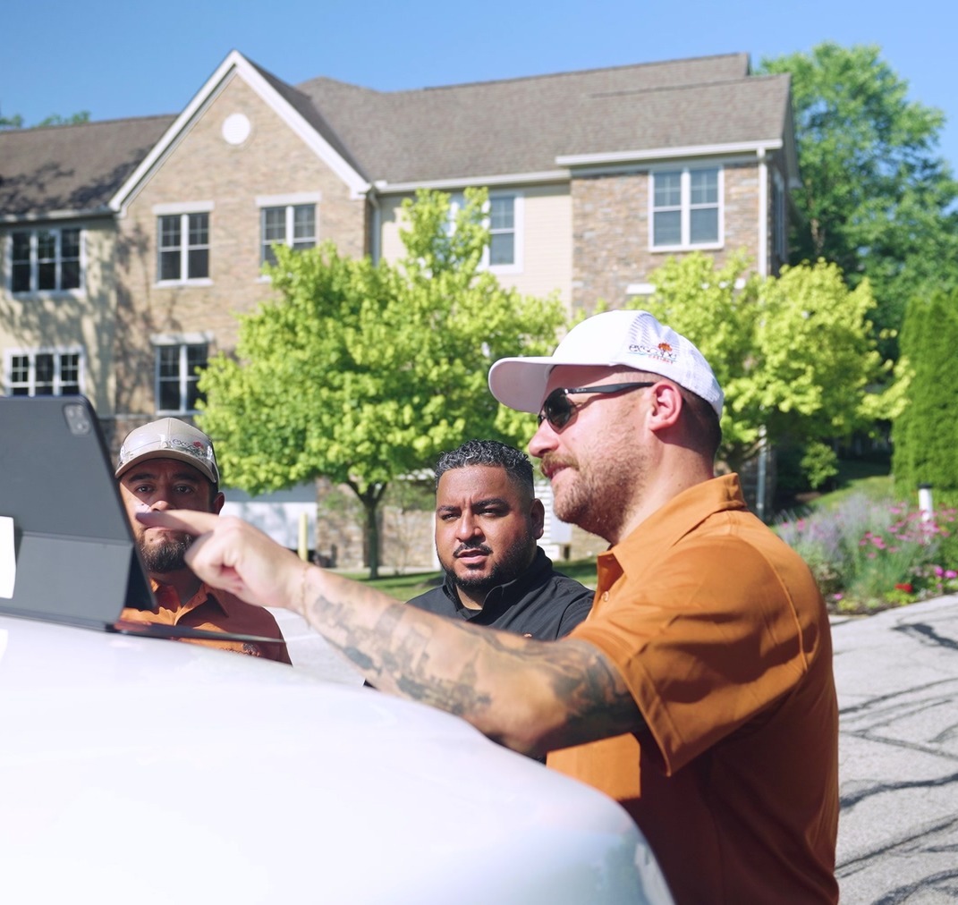 Exscape Group crew leader reviewing a tablet with the team on a truck hood