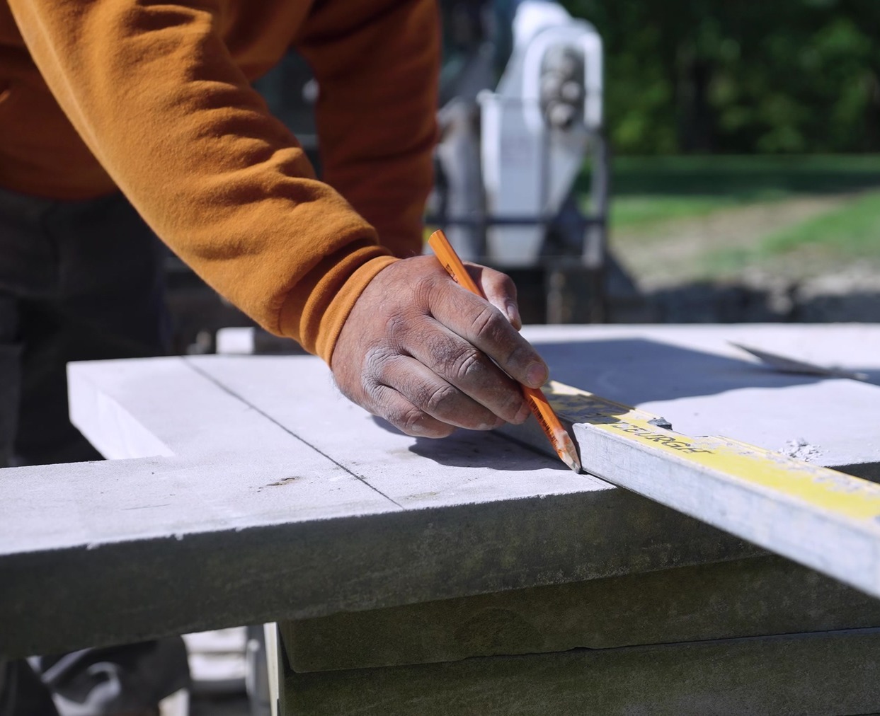 Exscape Group crew member marking a stone paver for a precise cut