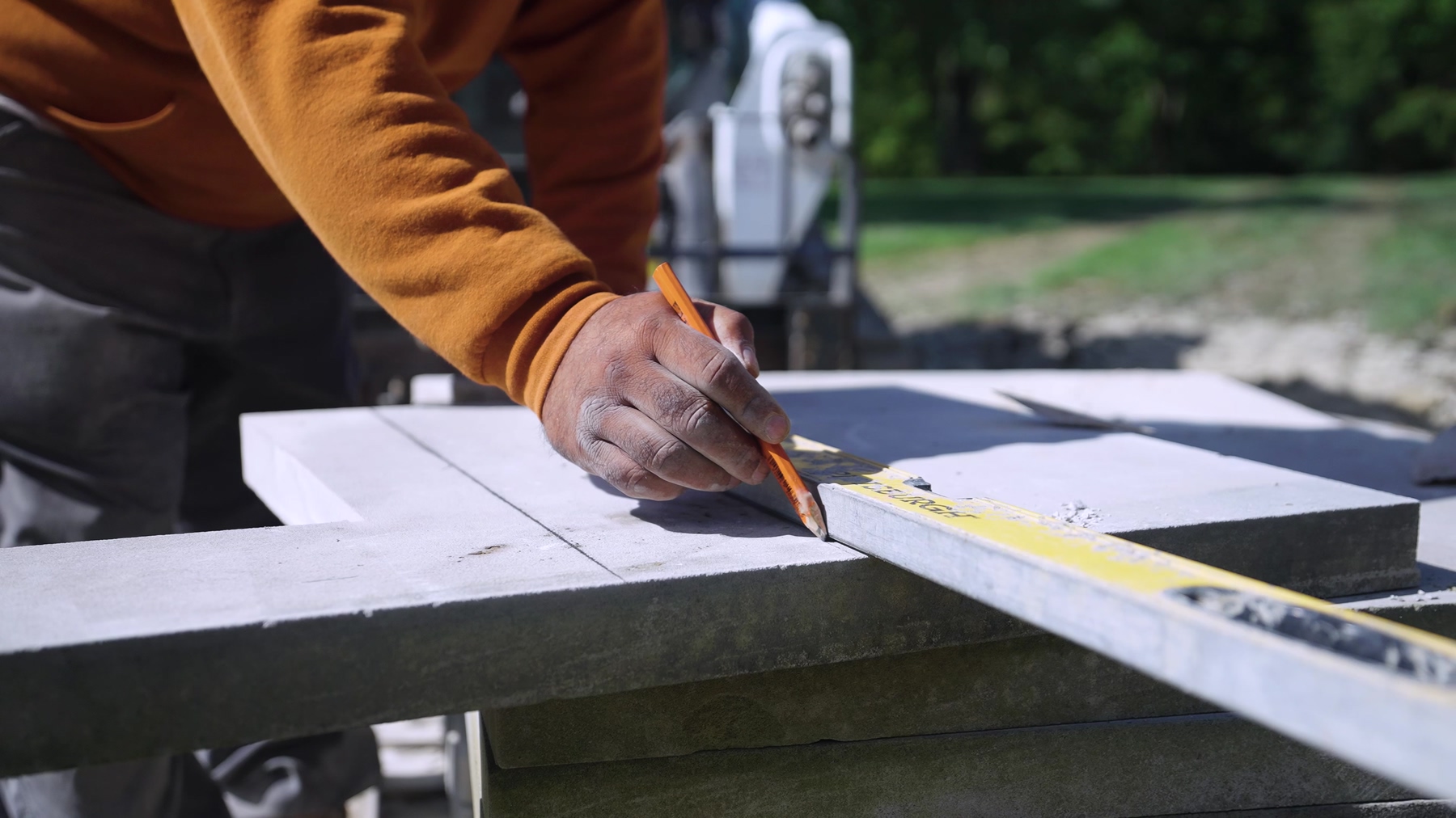 Exscape Group crew member marking a stone paver for a precise cut