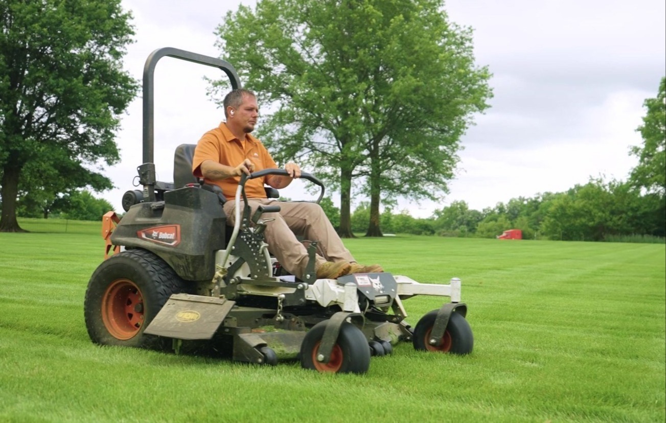 Exscape Group crew member mowing a large lawn on a zero-turn mower Exscape Group crew member mowing a large lawn on a zero-turn mower
