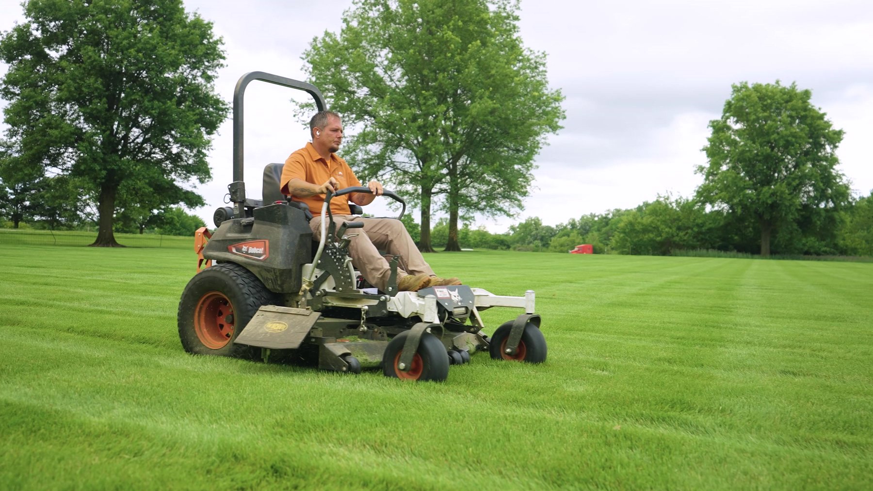 Exscape Group crew member mowing a large lawn on a zero-turn mower