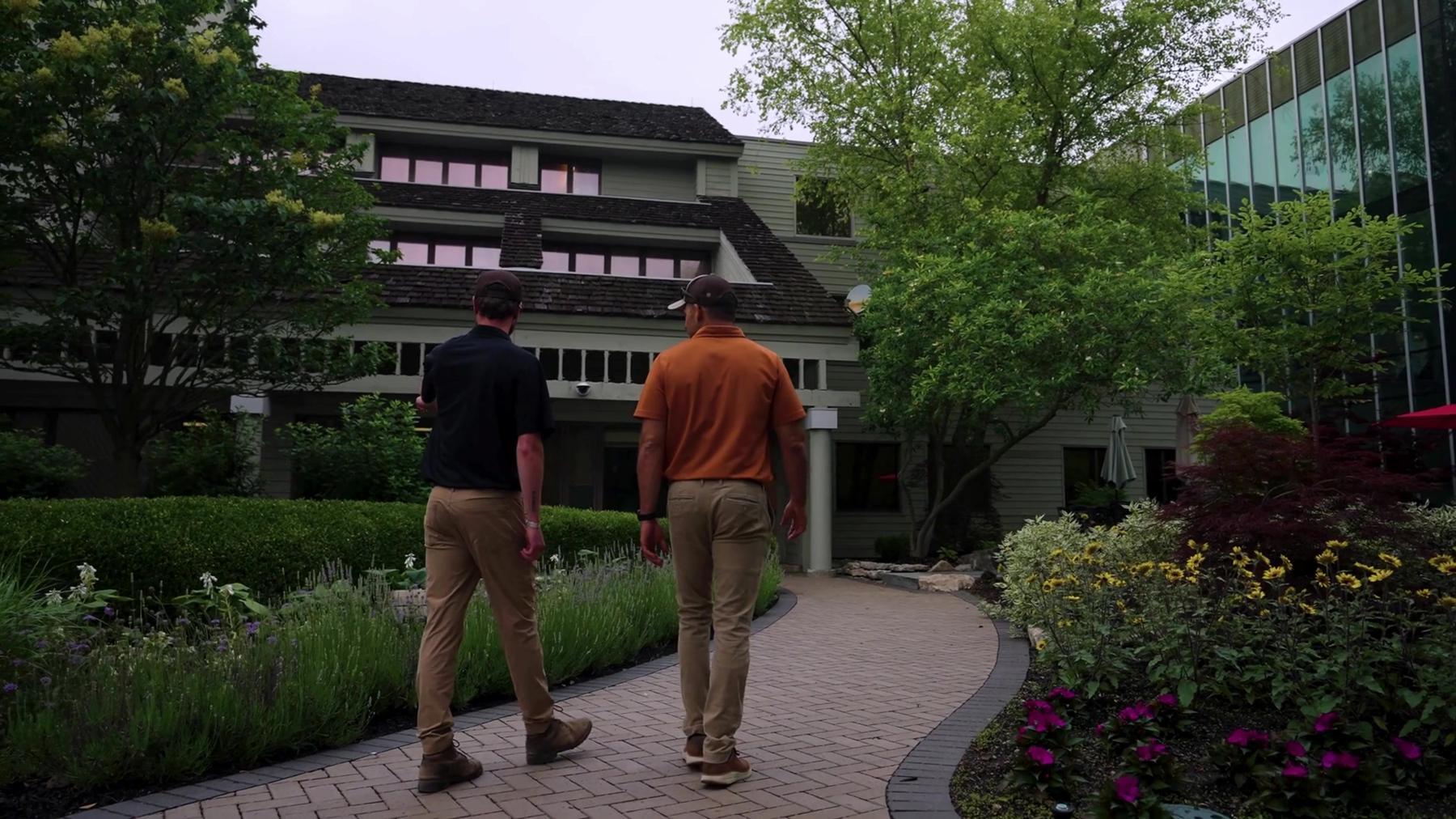 Exscape Group team members walking a paver path through landscaped gardens