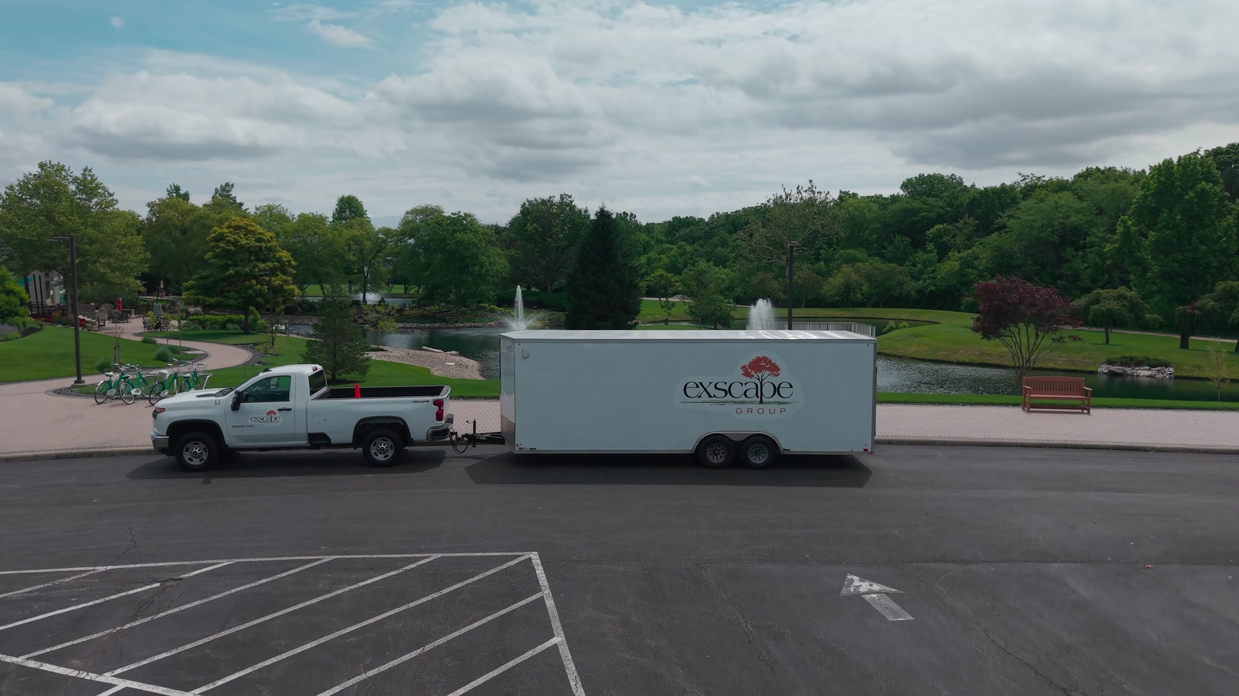 Exscape Group truck and trailer parked beside a campus pond