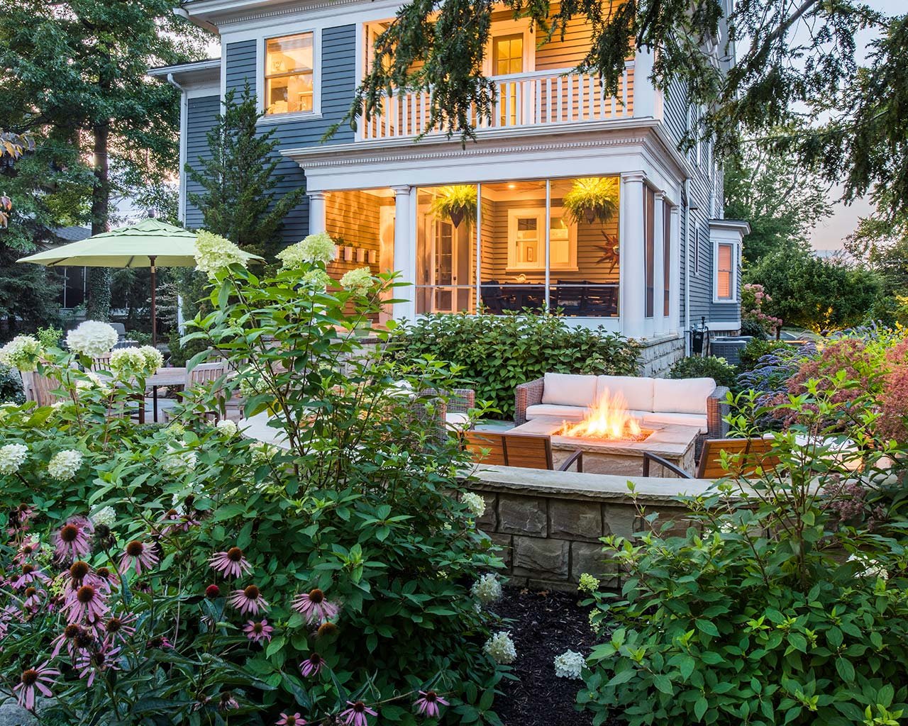 Patio with fire pit surrounded by flowering garden beds