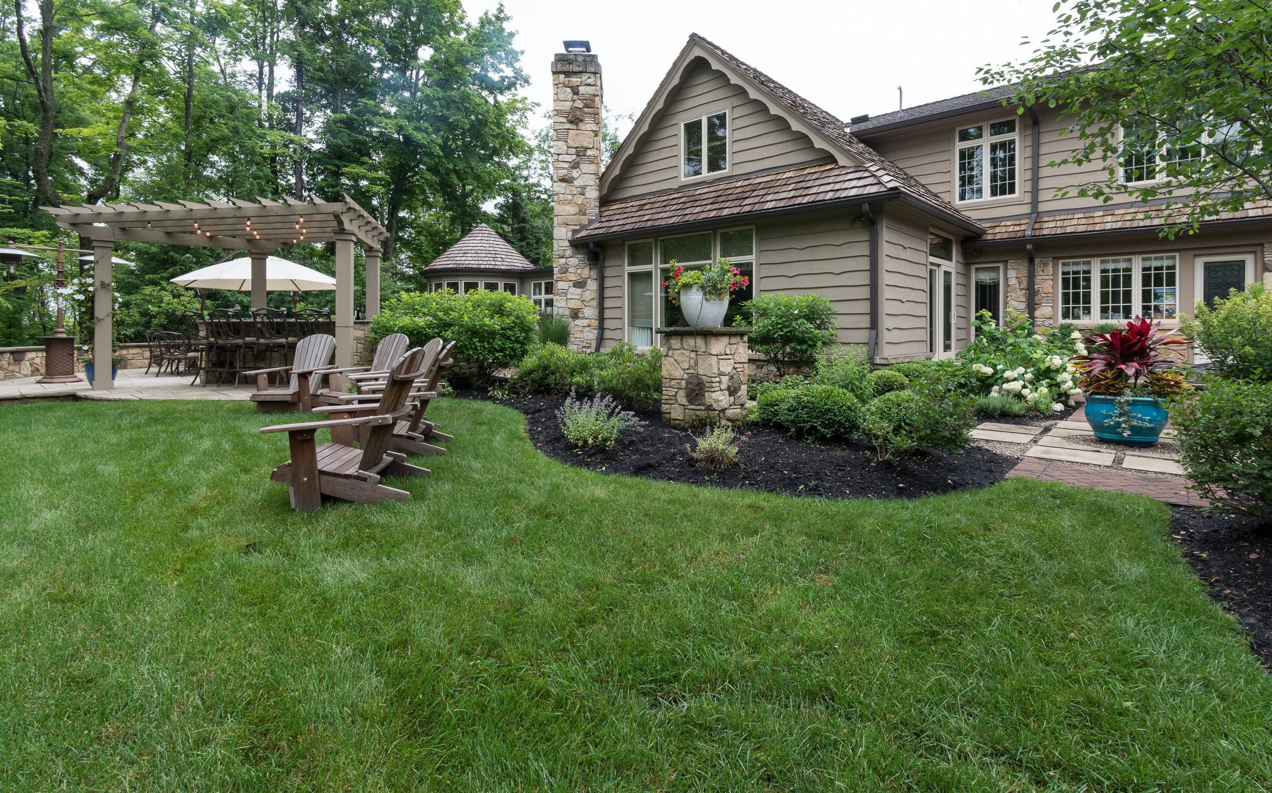 Manicured lawn and planting beds beside a stone home