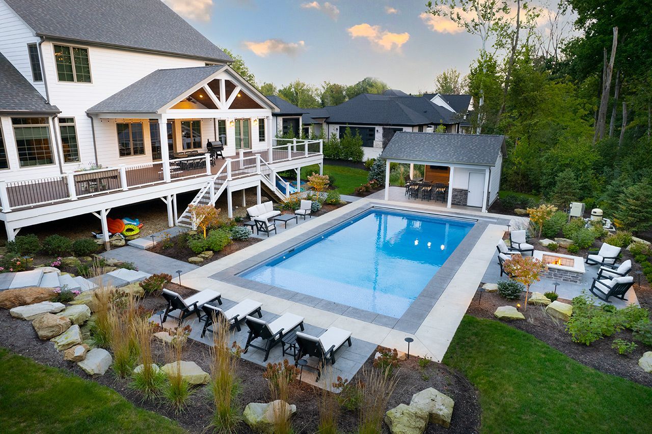 Inground pool, patio, and landscaping behind a two-story home
