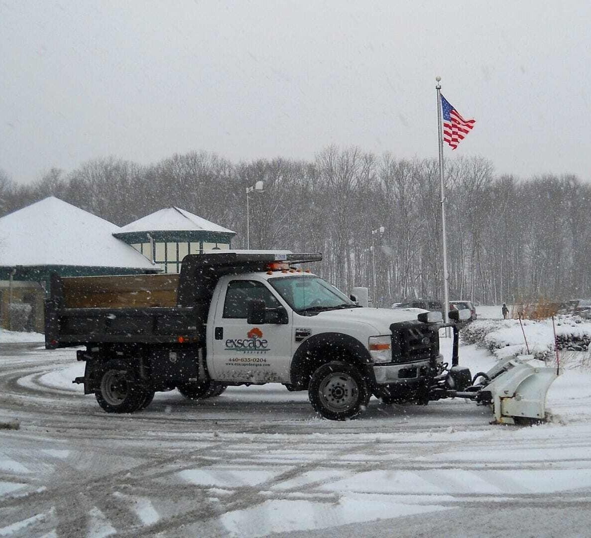 Snow plow truck clearing a commercial parking lot