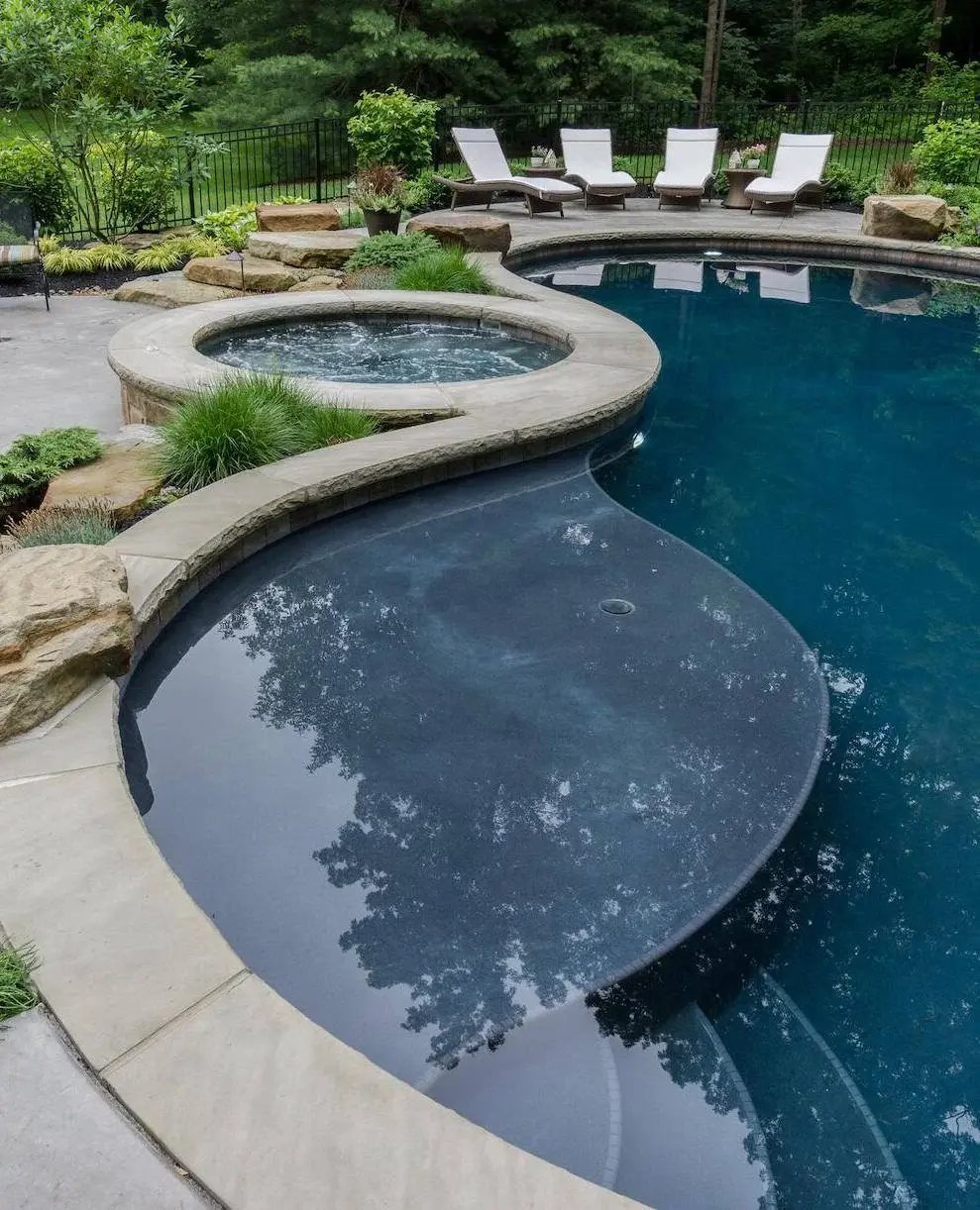 Custom freeform in-ground pool with raised spa and natural stone coping by Exscape Group in Bainbridge, OH