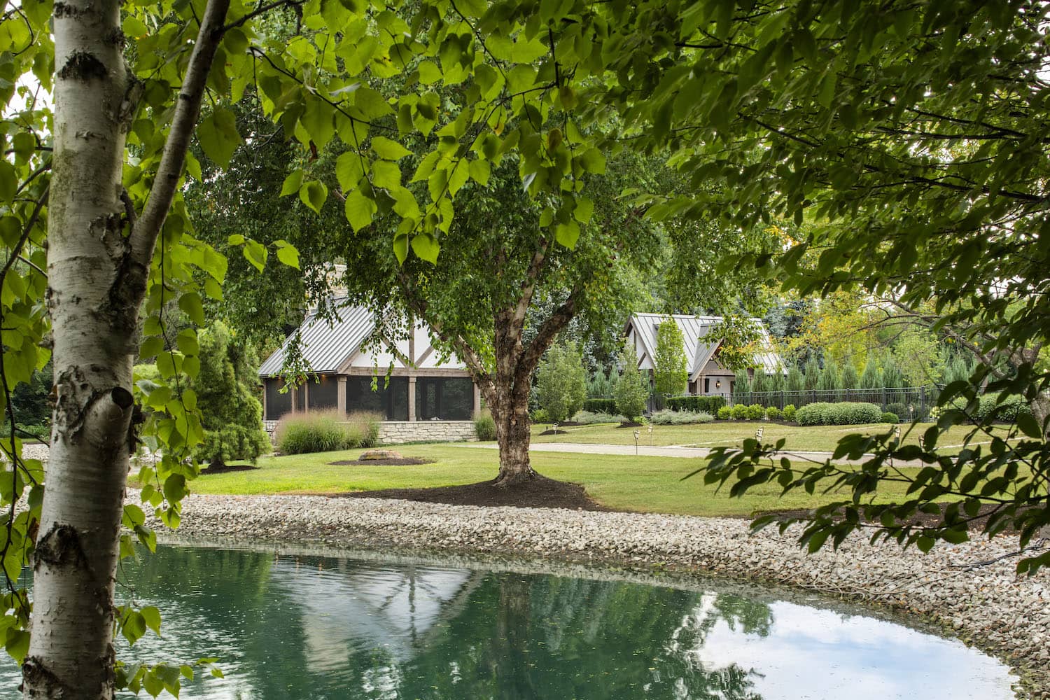 Luxury backyard patio with pergola, stone pillars, and pink hibiscus flowers surrounding an outdoor seating area in Ohio.