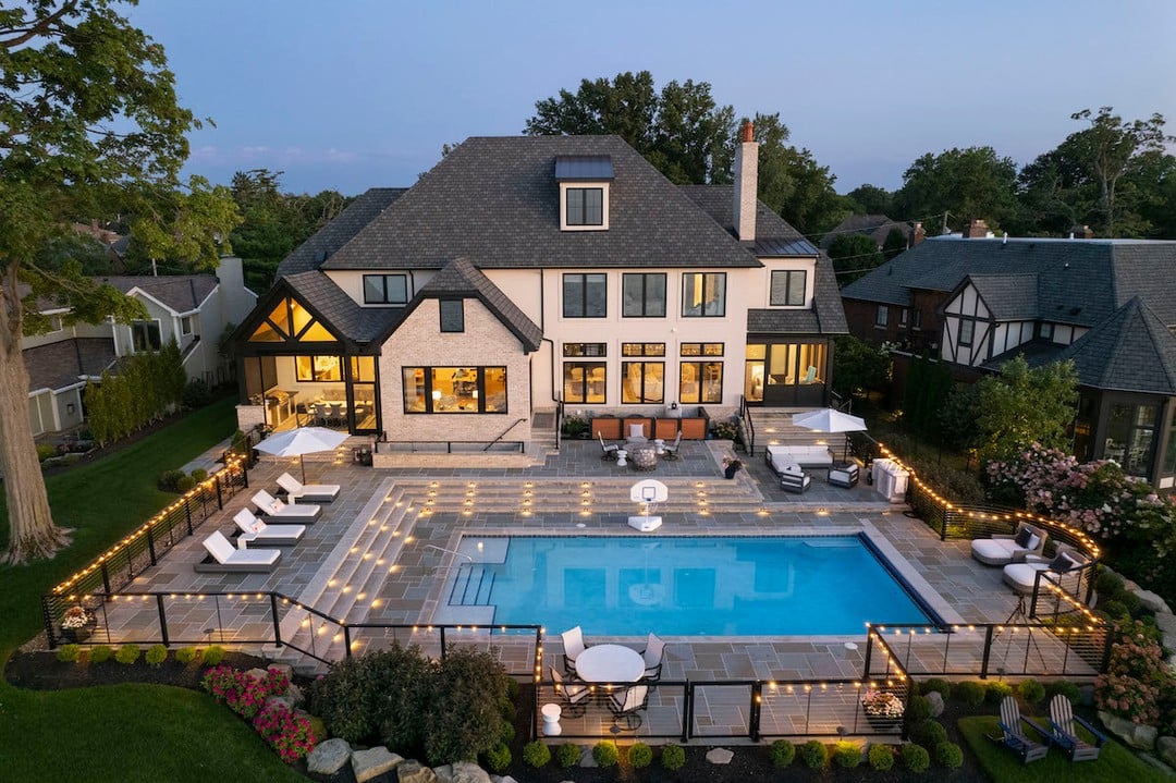 Luxury backyard with custom pool, stone patio, and landscape lighting designed by Exscape Group in Ohio