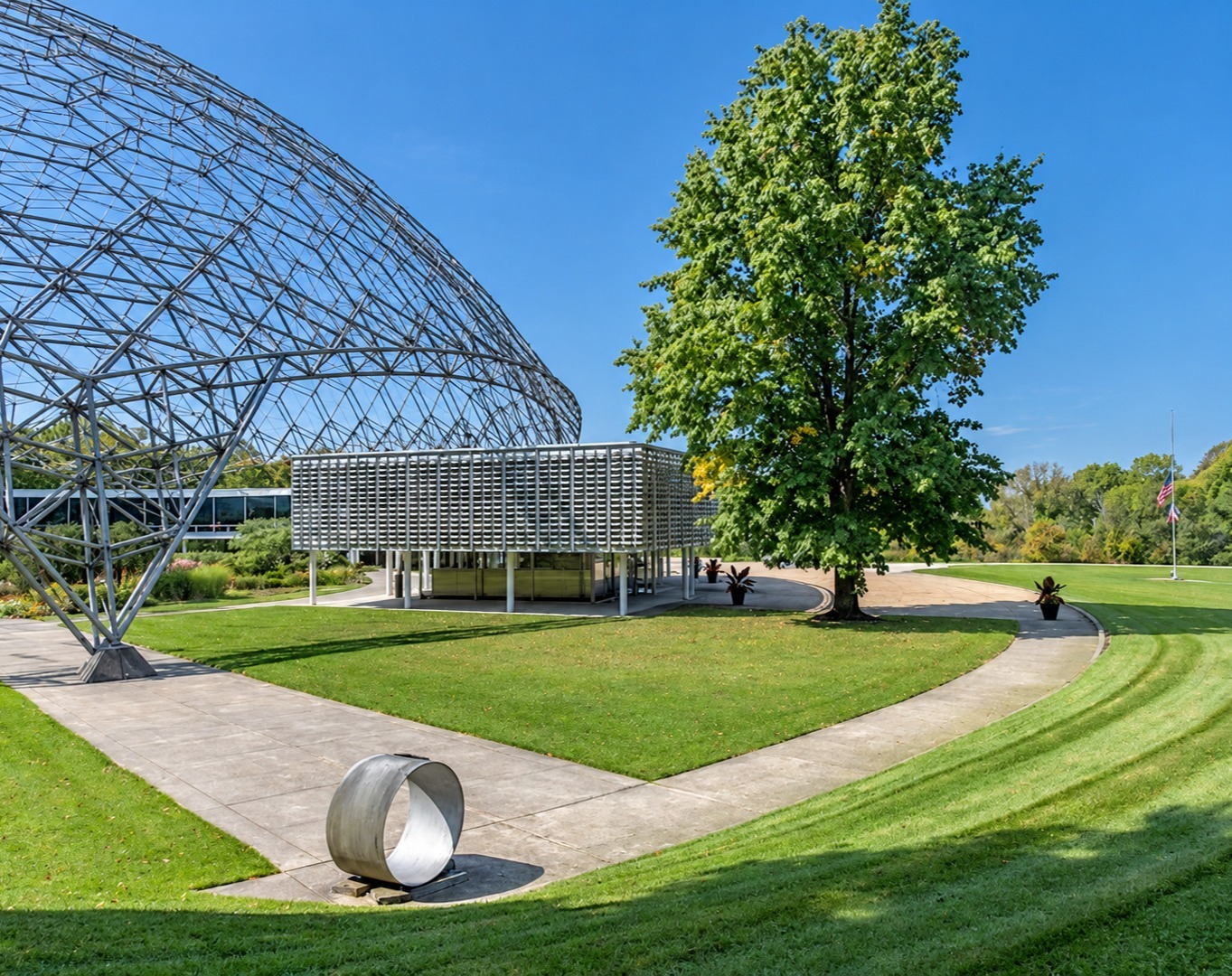 Landscaped grounds with lawn and shade tree beside a glass dome structure