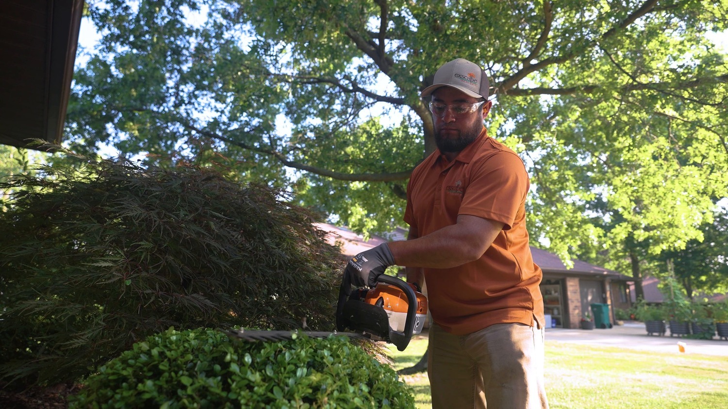 Exscape Group landscaper pruning shrubs during residential property maintenance