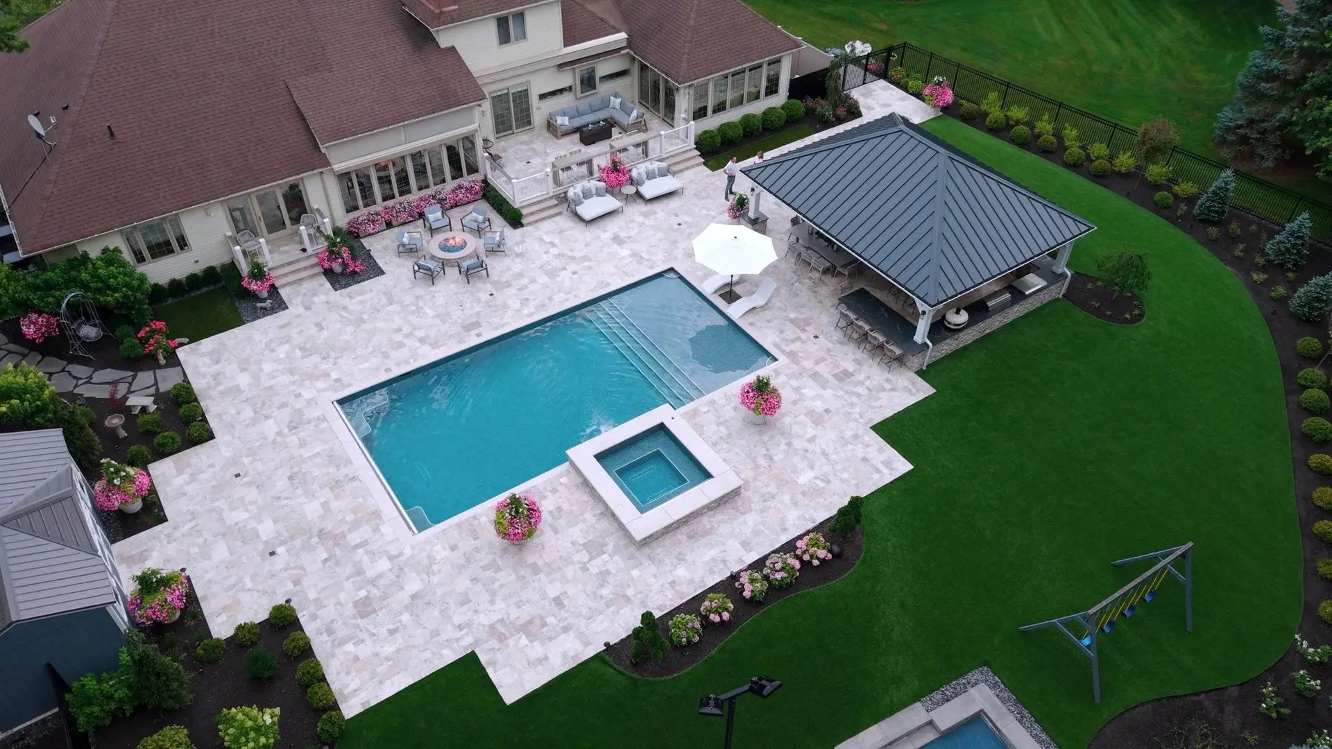 Aerial view of an inground pool and spa with stone patio