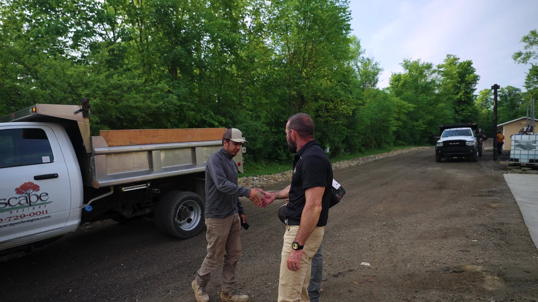 Exscape Group managers shaking hands beside a company dump truck